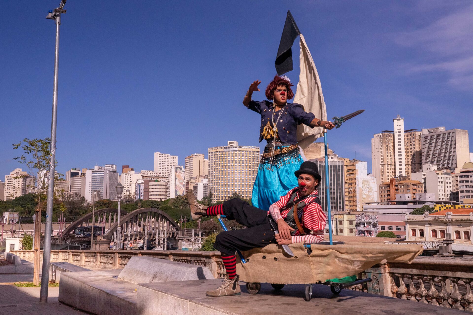 Dupla de palhaços-piratas do espetáculo Piratas do Curral, no Viaduto Santa Tereza com o skyline de BH ao fundo